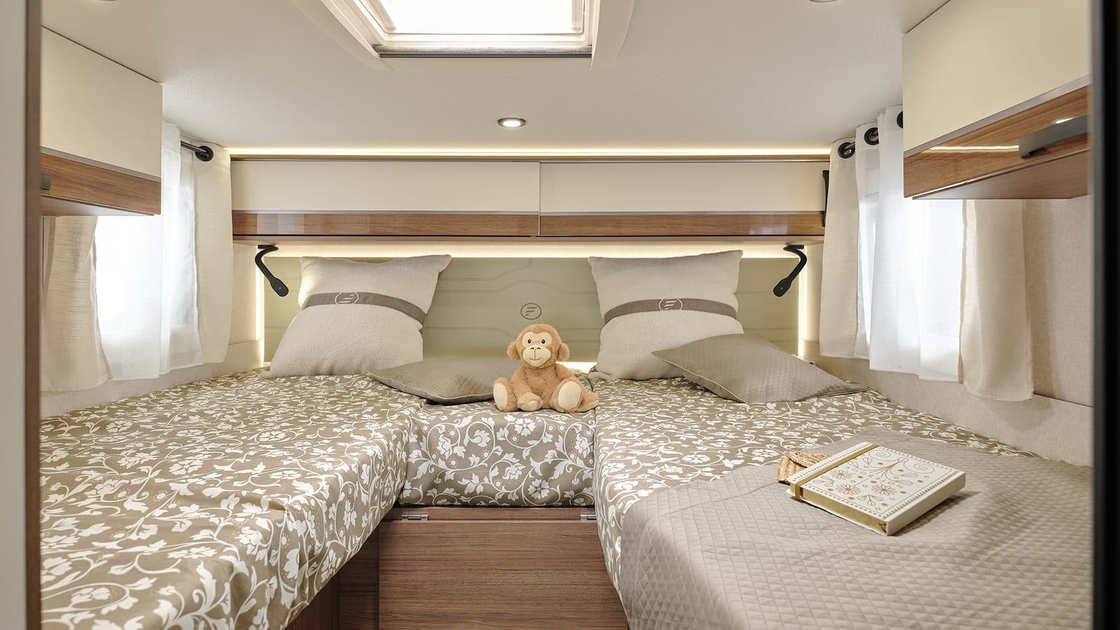 Chambre arrière du Fleurette Migrateur 69 LJG : deux lits jumeaux réunis par un coussin central, linge beige à motifs floraux, tête de lit rétroéclairée et lanterneau