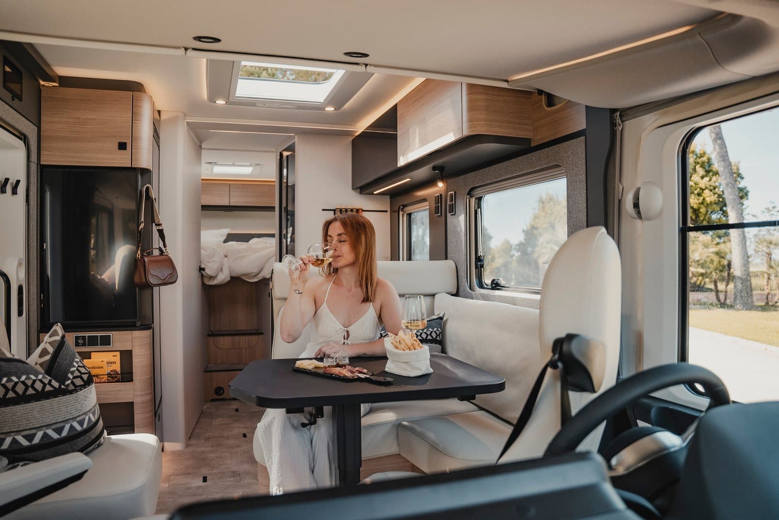 Salon lumineux du Hymer B-MC I 680 : dînette en bois clair, grandes baies vitrées et lanterneau panoramique